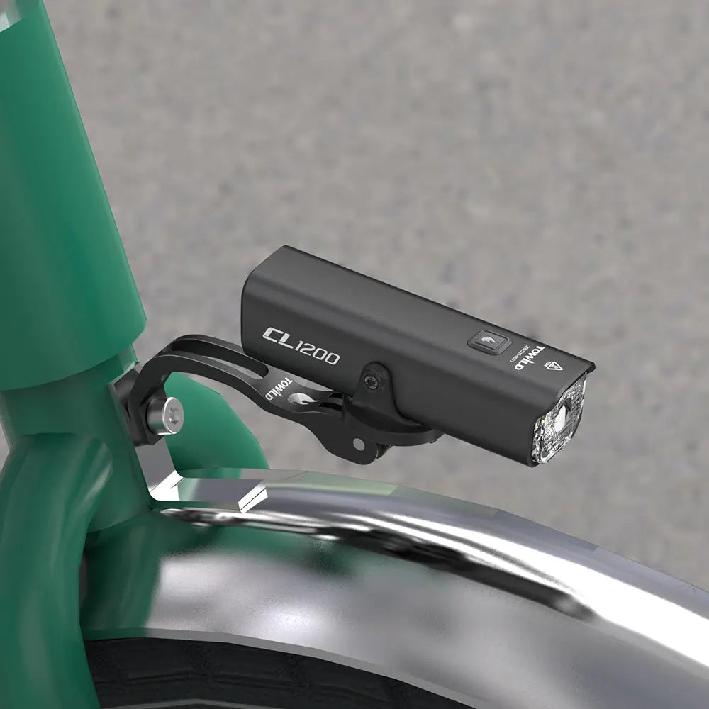 The TOWILD AS60 mount installed on the front fork of a green Brompton-style folding bike, holding a TOWILD CL1200 headlight in a clean, optimal position.