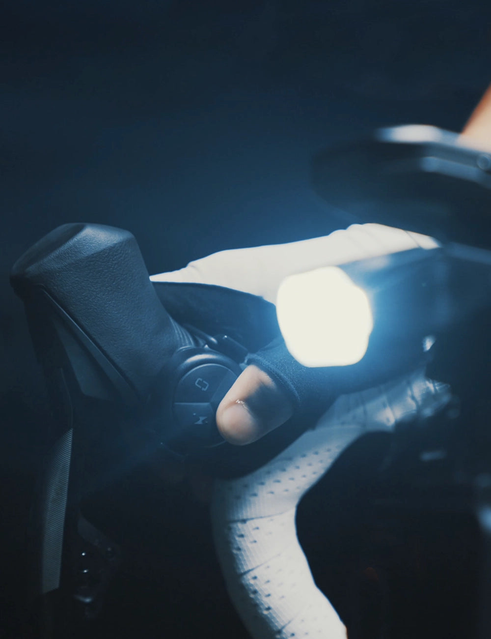 A gloved rider operates the handlebar remote beside an illuminated TOWILD BL1500 during a night ride.