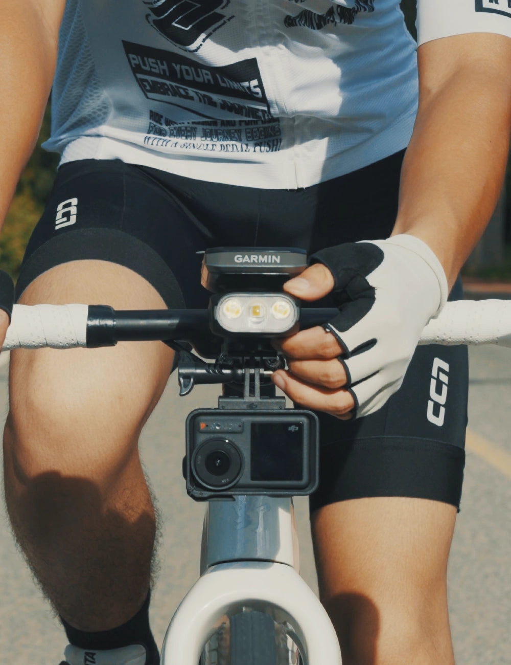 Front view of a cyclist with the TOWILD BL1500 mounted below a Garmin computer and above an action camera.
