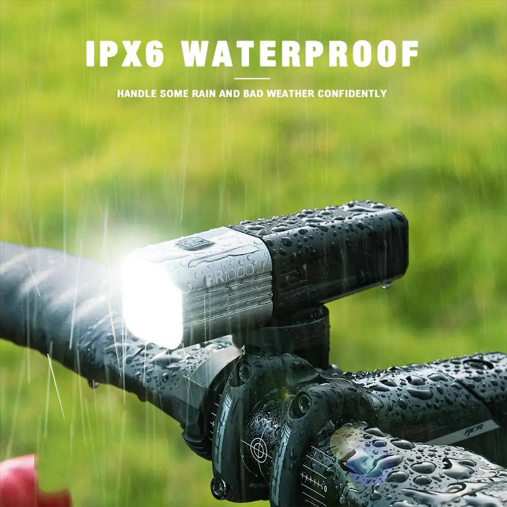 The IPX6 waterproof Towild BR1000 bike light shining brightly while mounted on a handlebar in heavy rain.