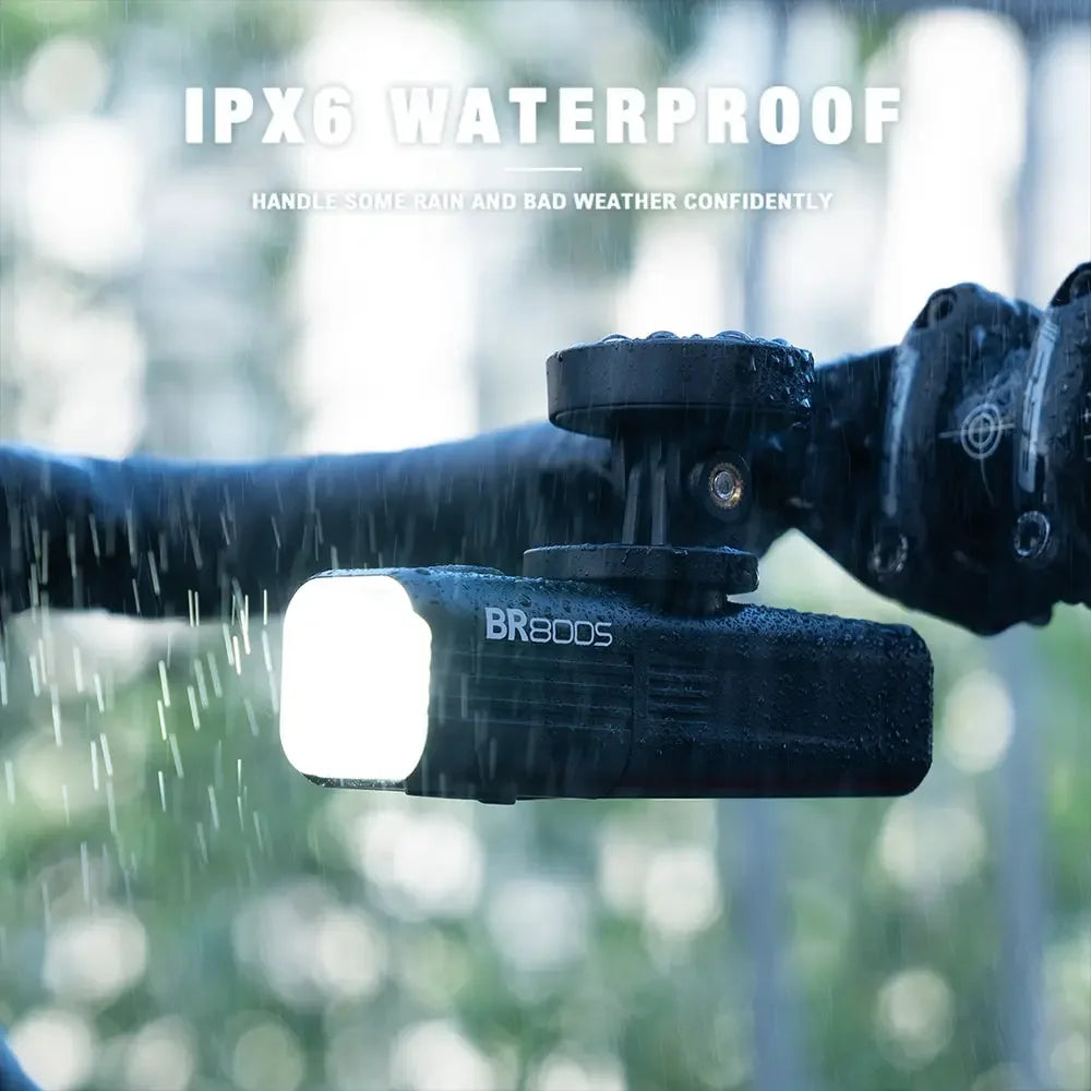The TOWILD BR800s bike light mounted under a bike computer, demonstrating its IPX6 waterproof capability in the rain.