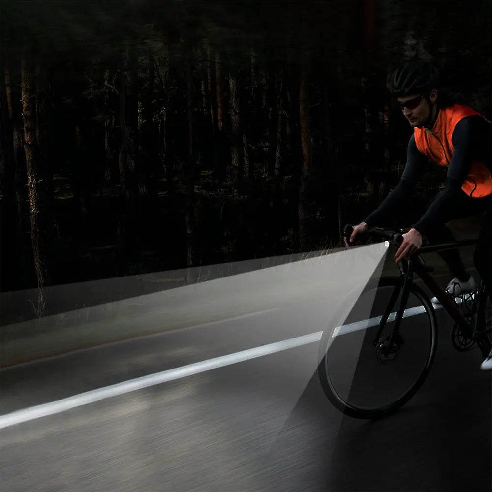 A cyclist riding at night, with the road ahead illuminated by the powerful and wide beam of the TOWILD CL1200 Pro.