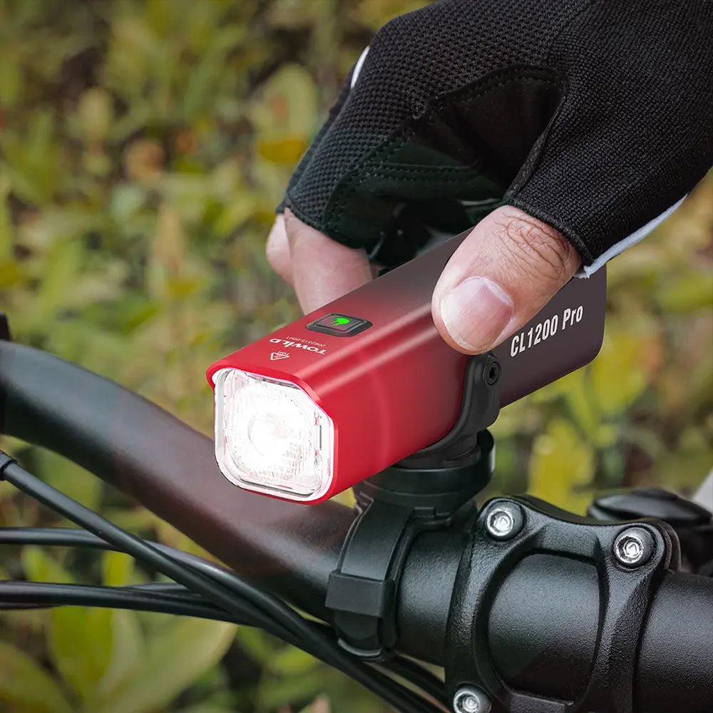 A cyclist's hand placing the TOWILD CL1200 Pro smart bike light onto a handlebar mount.