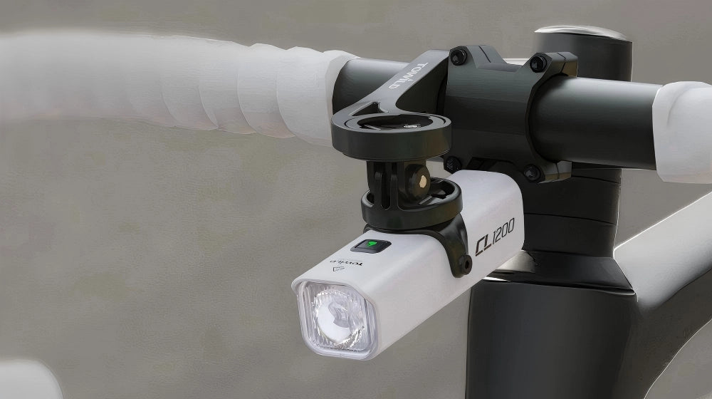 TOWILD CL1200 white bike headlight cleanly under-mounted beneath an out-front bracket using a GoPro adapter, saving handlebar space while maintaining the anti-glare beam.