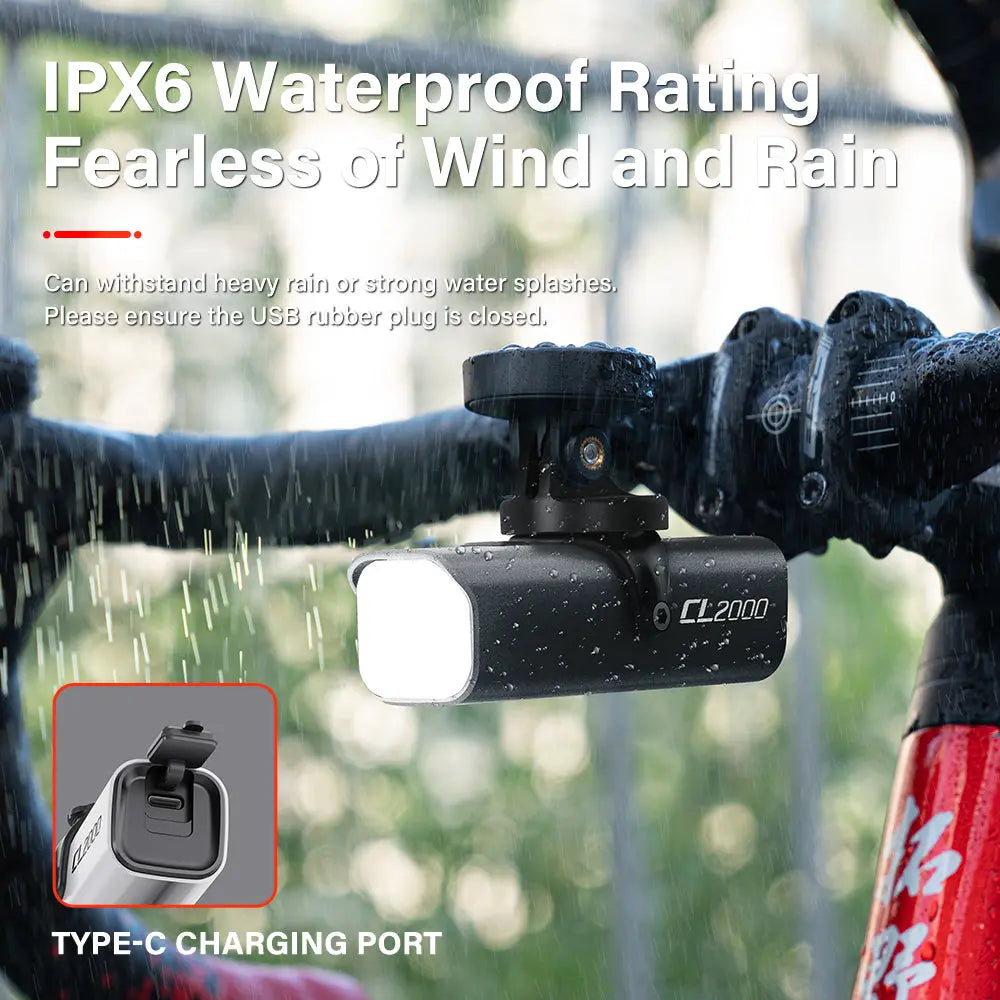 The IPX6 waterproof Towild CL2000 flagship bike light shining brightly while mounted on a handlebar in heavy rain. An inset shows the sealed USB-C charging port.