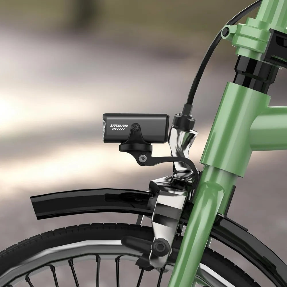 A close-up view of the TOWILD Urban Mini bike light seamlessly installed on the front fork of a green Brompton bike, showcasing its custom integrated mount.